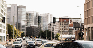  Straße in einer Stadt mit Mietpreisbremse und  vielen Autos im Vordergrund und dahinter mehrere Gebäude