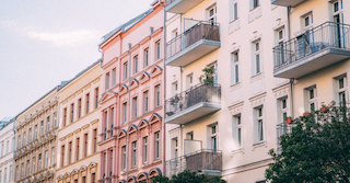 mehrere Hausfassaden von vorne fotografiert. Teilweise mit Balkon und in den Farben rot und leichtem gelb