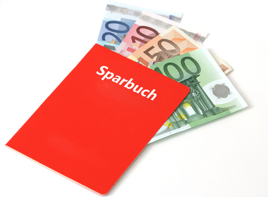 Rotes Sparbuch, in dem verschiedene Geldscheine enthalten sind. Symbolisiert das Sparbuch, in dem die Mietkaution angelegt werden kann