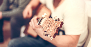  Eine Person mit weißem T-Shirt und Jeans spielt Gitarre, wie es im Mietvertrag geregelt wurde.