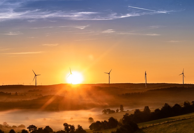 Windräder, die bei einem Sonnenaufgang zu sehen sind.